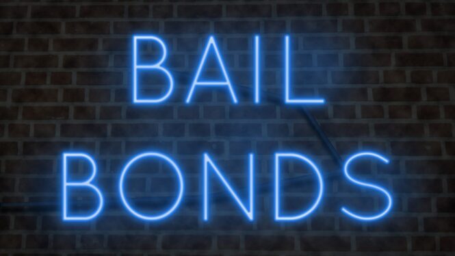 Neon BAIL BONDS sign on a brick wall at night